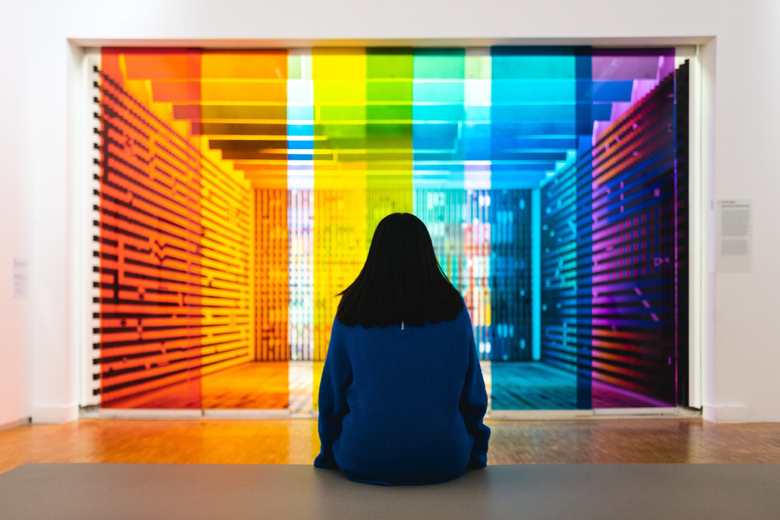 Visitor looking at a colourful artwork in a gallery.